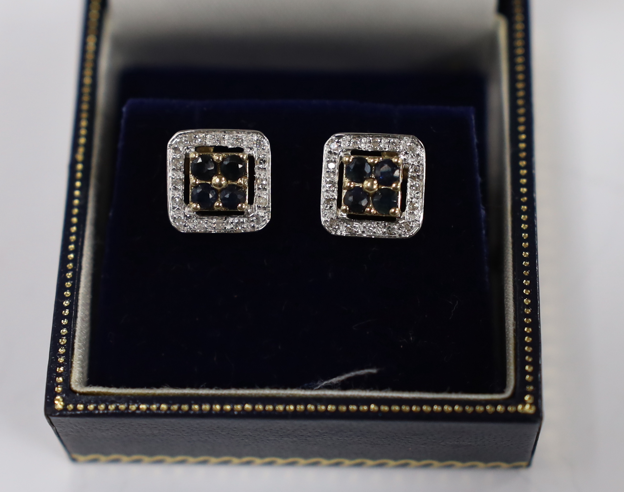 A modern pair of 375 yellow metal, sapphire and diamond chip set square cluster earrings, one butterfly missing, 10mm, gross weight 2.4 grams.